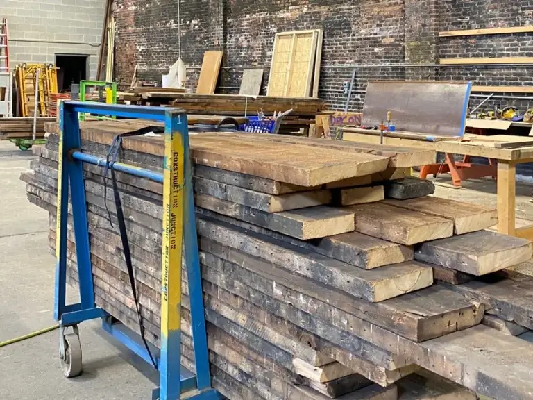 Deconstructed and reclaimed boards stacked on a dolly in a workshop